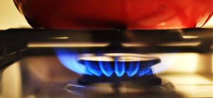 red frying pan standing on gas cooker being heated by blue gas flame